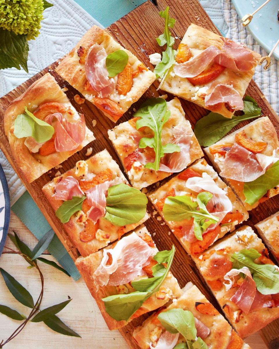 apricot prosciutto focaccia cut into squares on a wooden serving board