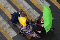 <p>A Indian girl holds an umbrella as she sits on a bicycle while crossing a road during heavy rain in Chennai on June 8, 2016. </p>