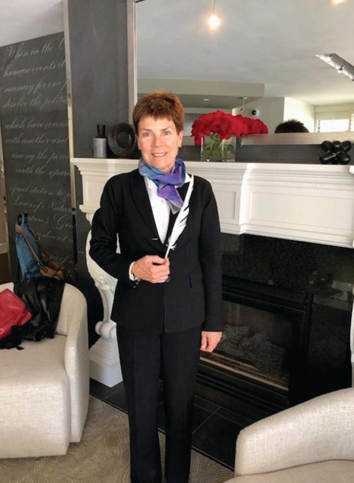 Terrie Harman posing in her hotel with the quill feather memento that the Court gives to attorneys who appear before them.