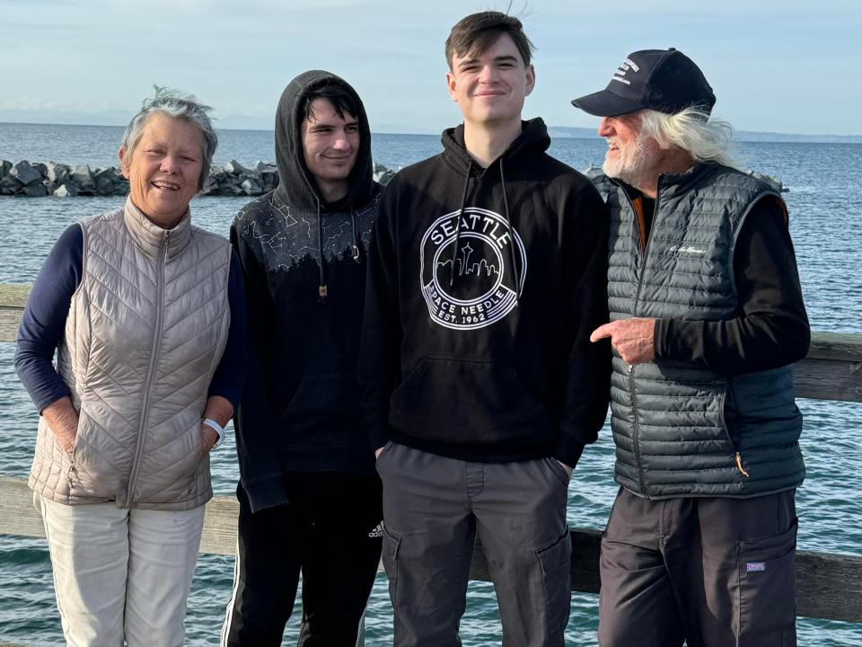 An older woman, two young men, and an older man at a seafront.