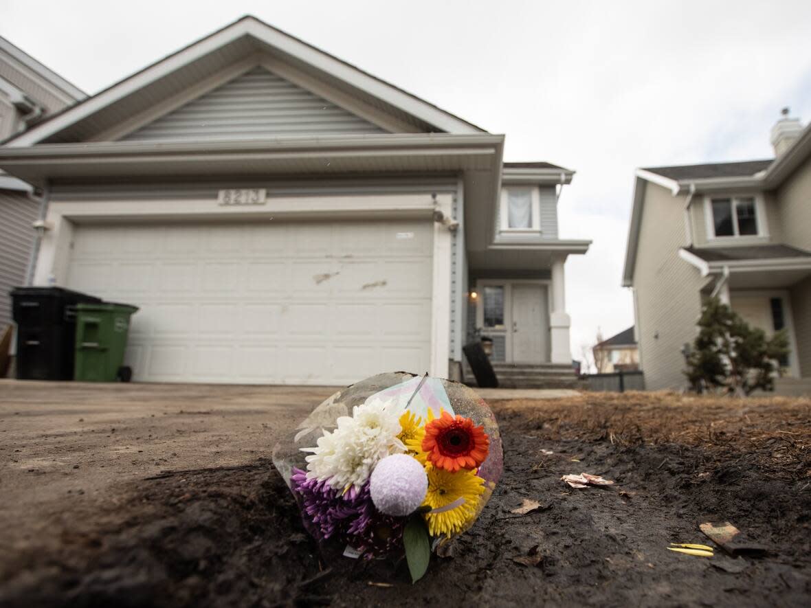 Flowers are placed in front of a house where an 11-year-old boy died after being attacked by two large dogs. (Jason Franson/The Canadian Press - image credit)