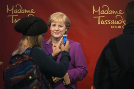 A tourist takes a picture of the wax figure of German Chancellor Angela Merkel at the Madame Tussauds wax museum in Berlin, September 19, 2013. REUTERS/Thomas Peter