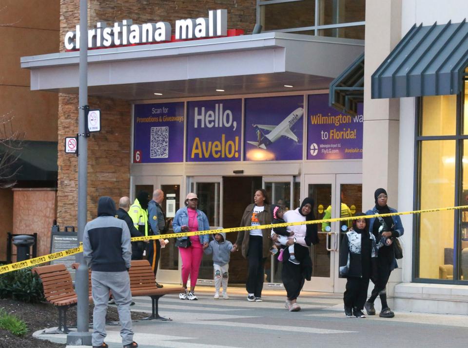 Shoppers leave the mall as police, fire and medical personnel respond in force to the food court entrance at the Christiana Mall after a shooting Saturday evening, April 8, 2023.