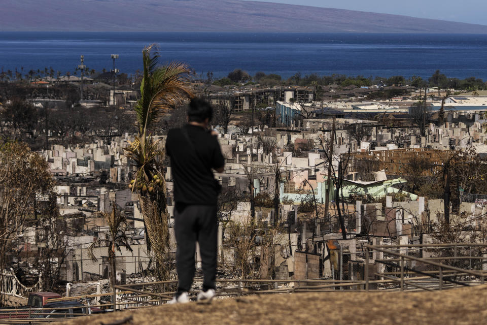 A person records the aftermath of a wildfire in Lahaina, Hawaii, Saturday, Aug. 19, 2023. (AP Photo/Jae C. Hong)