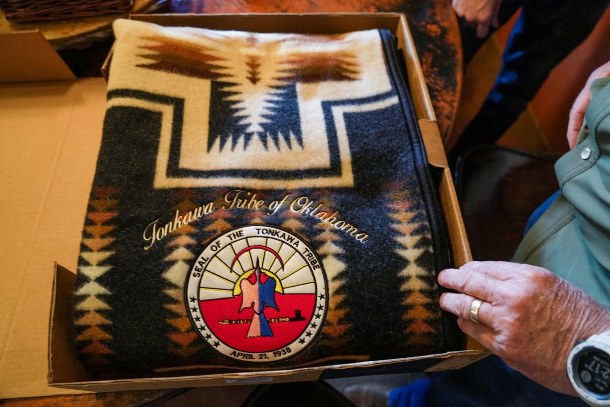 Racheal Starr, secretary-treasurer of the Tonkawa tribe, presents Dave Cunningham with a blanket bearing the seal of the Tonkawa tribe during a private luncheon.