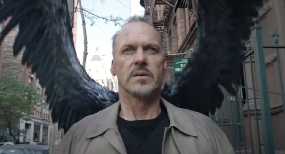 closeup of a man walking in the street with large black wings