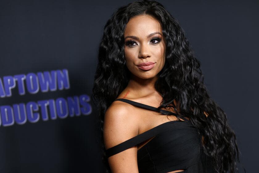 Erica Mena posing in a black dress against a black backdrop