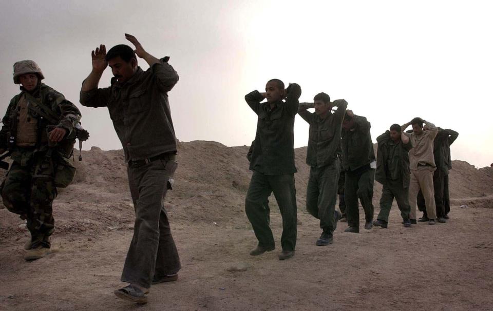 FILE - In this March 21, 2003, file photo, Iraqi soldiers surrender to U.S. Marines with India Co., 3rd Battalion, 7th Marines, 1st Marine Division following a gunfight at the headquarters of the Iraqi 51st and 32nd mechanized infantry divisions near Az Bayer, Iraq. The U.S. launched its invasion of Iraq on March 20, 2003, unleashing a war that led to an insurgency, sectarian violence and tens of thousands of deaths. (AP Photo/Laura Rauch, File)