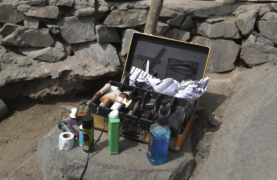 El portafolio dorado del peluquero de 21 años Josué Yacahuanca está sobre una roca en una colina en el barrio San Juan de Lurigancho en Lima, Perú, el viernes 19 de junio de 2020. (AP Foto/Martin Mejia)