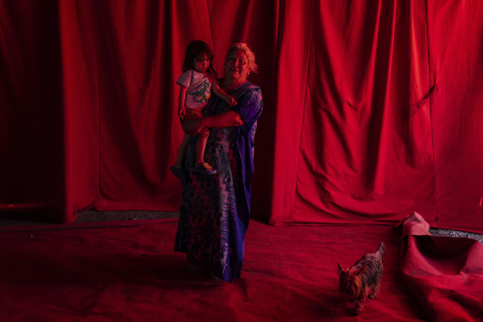 Kathy Fontey, a veteran cast member of the Timoteo Circus, poses for a photo holding her 3-year-old godchild, Florin, under a red canopy on the show’s current circus lot, on the outskirts of Santiago, Chile, Saturday, Dec. 10, 2022. Florin is the daughter of announcer Stéfano Rubio, who recently replaced his father Nano Rubio, the longtime announcer and artistic designer of Timoteo. (AP Photo/Esteban Felix)