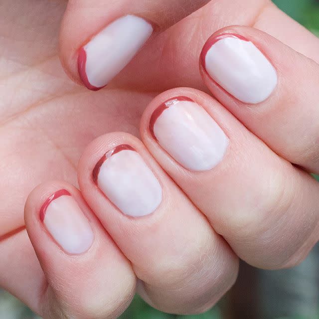 Superlong nails are not a prerequisite for a <a href="https://www.allure.com/gallery/french-manicure-french-tip-nail-designs?mbid=synd_yahoo_rss" rel="nofollow noopener" target="_blank" data-ylk="slk:French manicure;elm:context_link;itc:0;sec:content-canvas" class="link ">French manicure</a>, and neither is the typical white tips. Nail artist Kara Crevier used the <a href="https://oliveandjune.com/collections/nail-polish/products/the-nailfie-ready-box" rel="nofollow noopener" target="_blank" data-ylk="slk:Olive & June Nailfie Ready Box;elm:context_link;itc:0;sec:content-canvas" class="link ">Olive & June Nailfie Ready Box</a> to create a minimalist look that works so well for fall: a pale base with the thinnest stripes of a warm, rusty color at the tips.