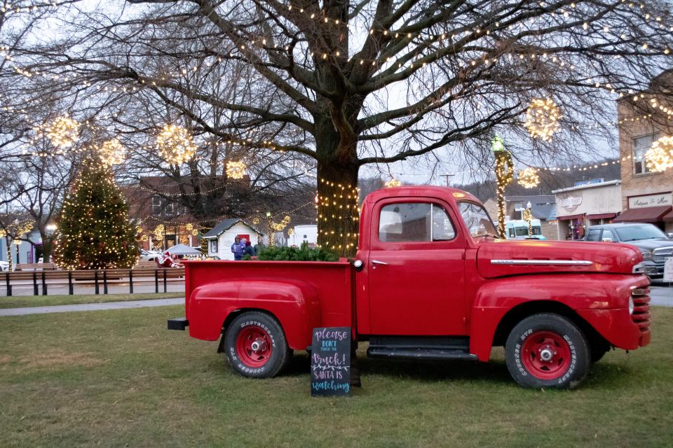 A vintage red Ford sits on the courthouse lawn in Caldwell, with the massive Christmas tree and Santa Claus behind it.