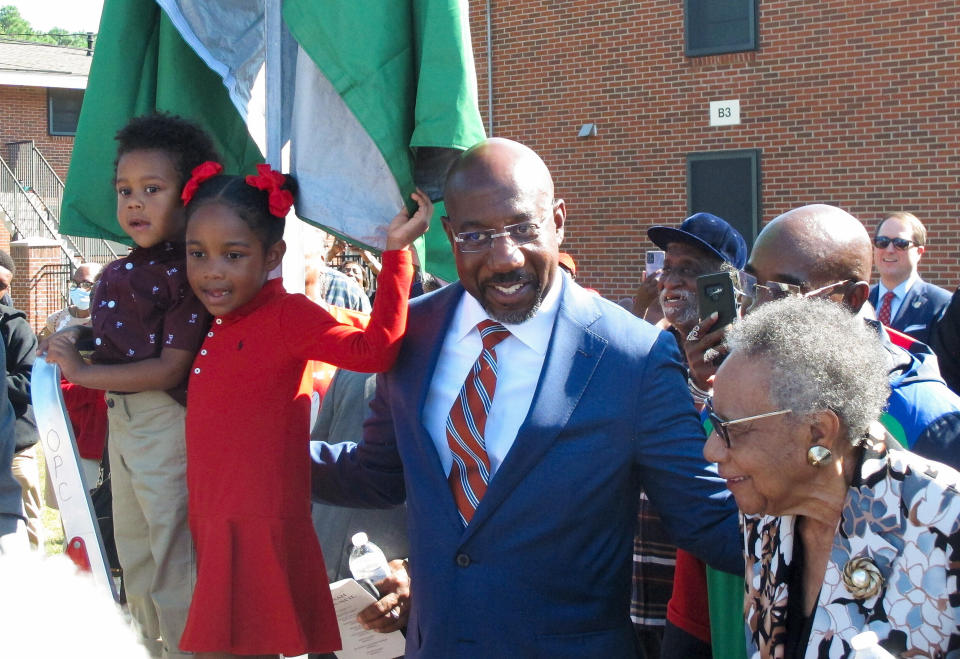 FILE - Sen. Raphael Warnock stands with his children, Caleb and Chloe, and his mother, Verlene Warnock, before unveiling a sign designating a street as Honorary Raphael Warnock Way in the Senator's hometown of Savannah, Ga., Oct. 6, 2022. Warnock, a freshman Democrat, is up for reelection in November in a pivotal race against Republican and former football star Herschel Walker. (AP Photo/Russ Bynum, File)