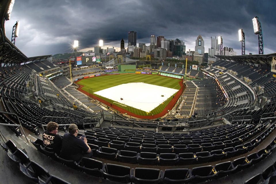 Fans sit under cover in the upper deck of PNC Park as the field remains covered during a rain delay before a baseball game between the Pittsburgh Pirates and the Detroit Tigers in Pittsburgh, Tuesday, June 7, 2022. (AP Photo/Gene J. Puskar)