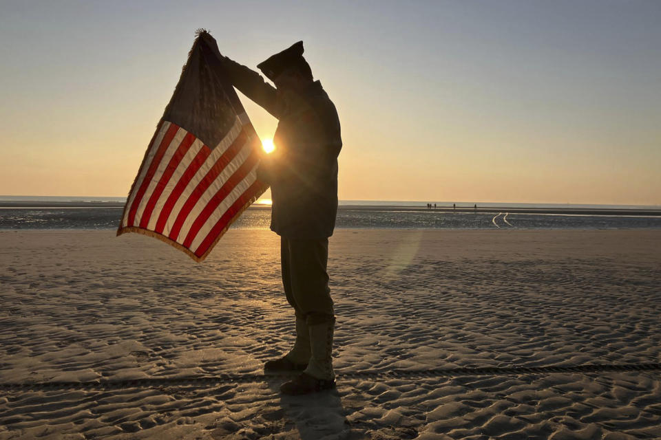 Christophe Receveur, of France, unfurls an American flag he bought six month ago in Gettysburg, Penn., to mark D-Day, Thursday, June 6, 2024 on Utah Beach, Normandy. (AP Photo/John Leicester)