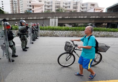 A man pushes his bicycle as police officers block the road in Tin Shui Wai in Hong Kong