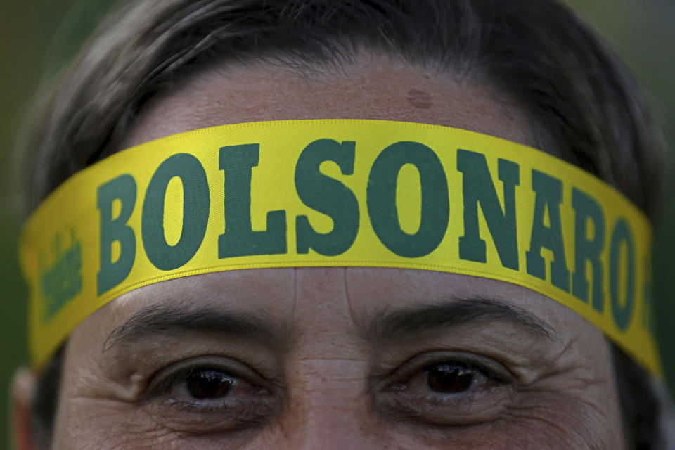 A supporter of presidential front-runner Jair Bolsonaro wears a headband supporting his candidate as he waits with others for election results outside the National Congress in Brasilia, Brazil, Sunday, Oct. 28, 2018. Brazilian voters decide who will next lead the world's fifth-largest country, the left-leaning Fernando Haddad of the Workers' Party, or far-right rival Bolsonaro of the Social Liberal Party. (AP Photo/Eraldo Peres)
