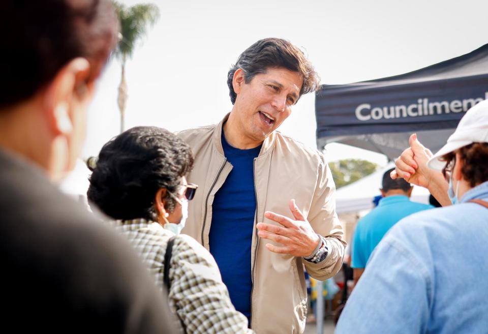 A man talks to several people outdoors.