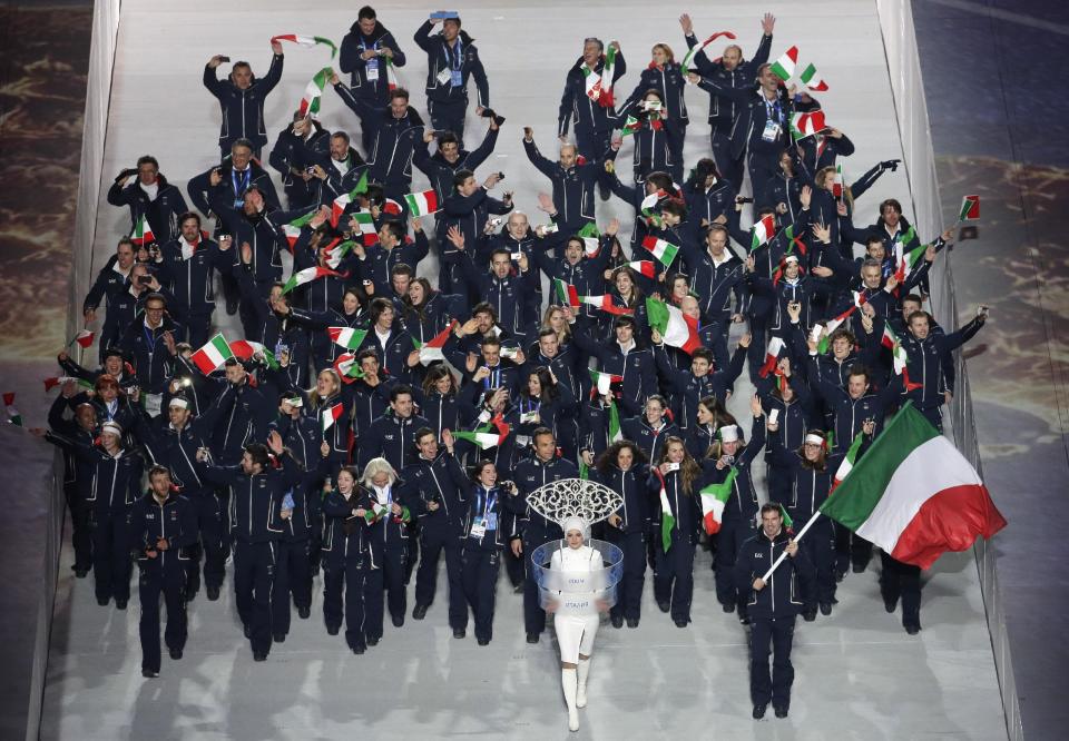 Armin Zoeggeler of Italy holds the national flag and enters the arena with his teammates during the opening ceremony of the 2014 Winter Olympics in Sochi, Russia, Friday, Feb. 7, 2014. (AP Photo/Charlie Riedel)