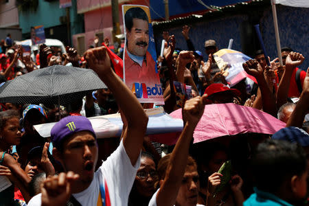 Supporters of Venezuela's President Nicolas Maduro hold placards with his image as they attend a campaign rally in Caracas, Venezuela May 16, 2018. Picture taken May 16, 2018. REUTERS/Carlos Garcia Rawlins