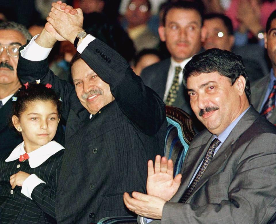 FILE - This file photo dated 1999 shows Algerian President Abdelaziz Bouteflika, left, waving next to his adviser Ali Benflis during meeting in Algiers, Algeria. Unidentifed girl at left. The Algerian government announced Friday, Jan. 17, 2014 the official date of its presidential elections, yet with just 90 days to go before one of the most important votes in its history, it is not yet clear who is even running. The presidential elections, now scheduled for April 17, could possibly see the handing over of power to a new generation and for the first time Algeria would be led by someone who didn’t fight in the 1958-1962 war for independence against France. (AP Photo, File)