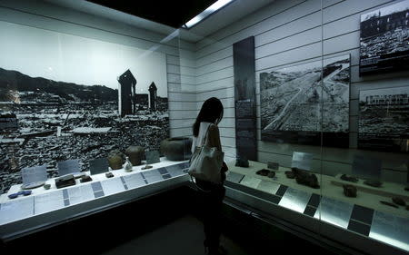 A visitor looks at photographs showing Nagasaki city after the 1945 atomic bombing and artifacts from the destruction caused by the bomb, at the Nagasaki Atomic Bomb Museum in Nagasaki, western Japan, August 8, 2015, on the eve of the 70th anniversary of the bombing of Nagasaki. REUTERS/Toru Hanai/Files