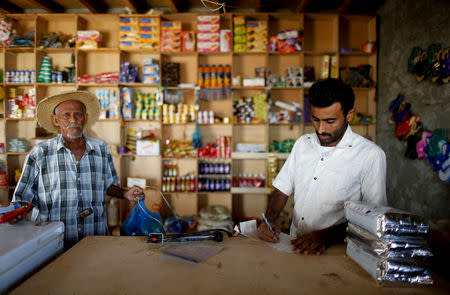 A customer stands by as a vendor calculates at a shop near the village of al-Jaraib, in the northwestern province of Hajjah, Yemen, February 20, 2019. REUTERS/Khaled Abdullah