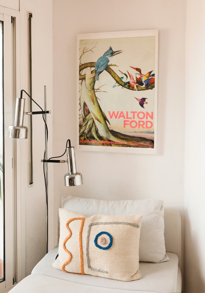 corner of white room with floor lamp, daybed with pillows, and art