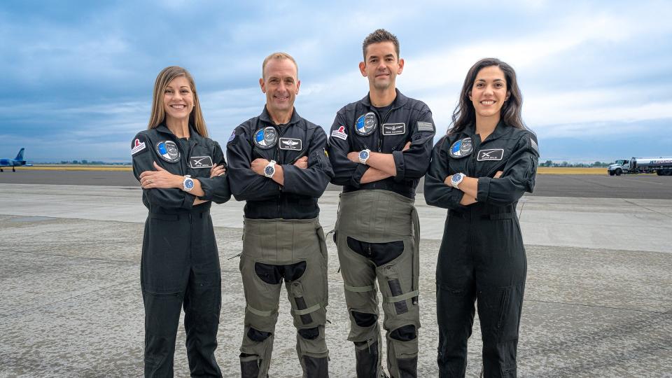 four people stand on a runway with their arms crossed over their chests