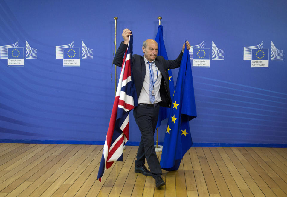 FILE - In this June 19, 2017 file photo, a member of protocol changes the EU and British flags at EU headquarters in Brussels. British lawmakers on Tuesday, Jan. 15, 2019 overwhelmingly rejected Prime Minister Theresa May's divorce deal with the European Union, plunging the Brexit process into chaos. (AP Photo/Virginia Mayo, File)