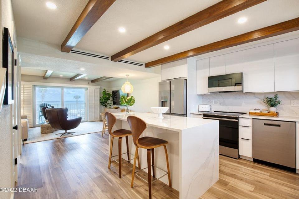This beautifully updated kitchen is covered in quartz, including the waterfall island, countertops and walls from the counters to the ceiling, and features white high-gloss custom-built cabinets, GE Café appliances, Calphlon cookware and Crate & Barrel glasses and dishes.