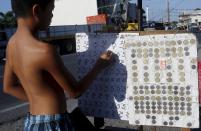 A teenager places bets on a numbers game along a road in San Fernando city, north of Manila, Philippines, March 7, 2015. When paying your final respects for a relative or friend, the last thing you might expect to see at the wake is people placing bets on a card game or bingo. Not in the Philippines. Filipinos, like many Asians, love their gambling. But making wagers on games such as "sakla", the local version of Spanish tarot cards, is particularly common at wakes because the family of the deceased gets a share of the winnings to help cover funeral expenses. Authorities have sought to regulate betting but illegal games persist, with men and women, rich and poor, betting on anything from cockfighting to the Basque hard-rubber ball game of jai-alai, basketball to spider races. Many told Reuters photographer Erik De Castro that gambling is only an entertaining diversion in a country where two-fifths of the population live on $2 a day. But he found that some gamble every day. Casino security personnel told of customers begging to be banned from the premises, while a financier who lends gamblers money at high interest described the dozens of vehicles and wads of land titles given as collateral by those hoping lady luck would bring them riches. REUTERS/Erik De Castro PICTURE 28 OF 29 FOR WIDER IMAGE STORY "HIGH STAKES IN MANILA". SEARCH "BINGO ERIK" FOR ALL IMAGES.