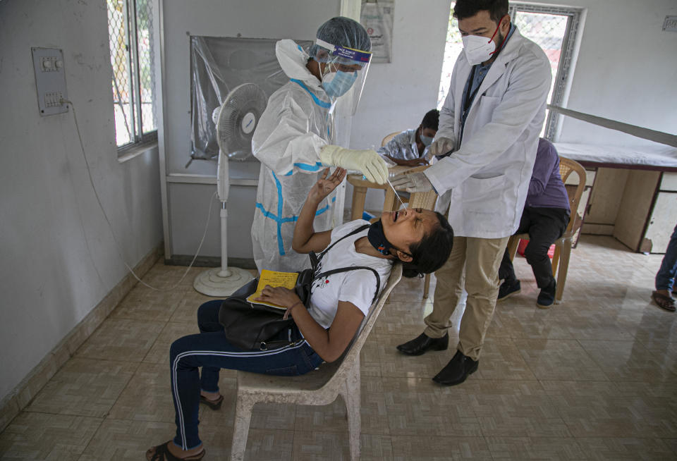 A health worker takes a nasal swab sample of a girl to test for COVID-19 during a random test for the family members of army personnel at the army base hospital in Gauhati, India, Monday, Oct. 19, 2020. (AP Photo/Anupam Nath)