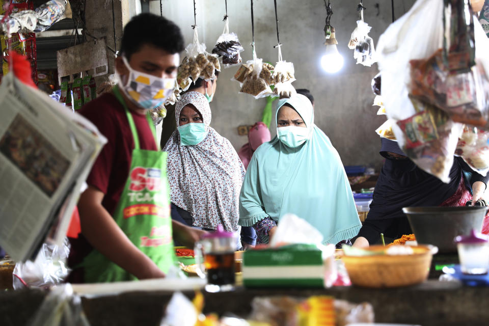 People wear masks at a traditional market in Jakarta, Indonesia, Friday, April 10, 2020. Authorities began stricter measures to halt the new coronavirus' spread in Indonesia's capital Friday, with its normally congested streets empty after death toll spiked in the past week. (AP Photo/Achmad Ibrahim)