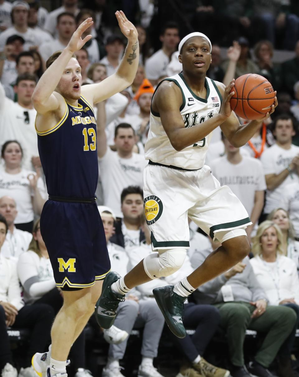 Michigan State guard Cassius Winston (5) passes the ball as Michigan forward Ignas Brazdeikis (13) defends during the first half of an NCAA college basketball game Saturday, March 9, 2019, in East Lansing, Mich. (AP Photo/Carlos Osorio)
