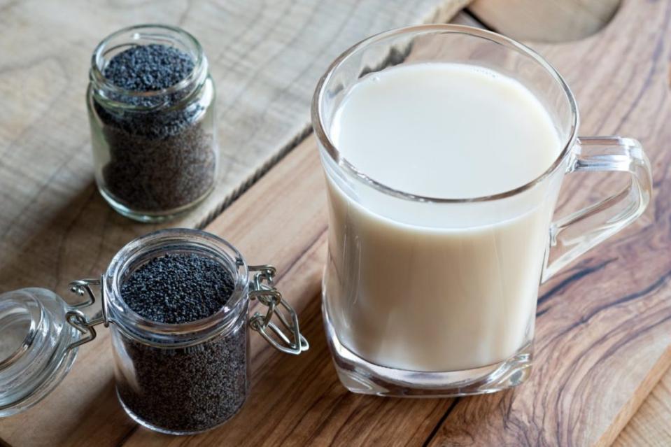 A jar of poppy seeds with a glass of fresh poppy seed milk