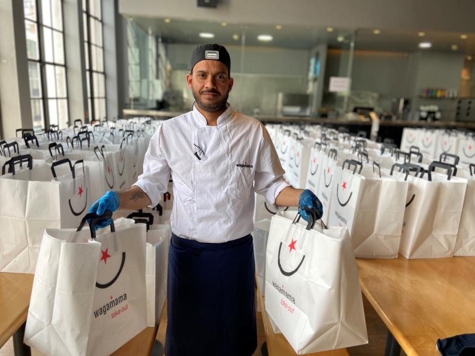 A Wagamama employee holding two takeaway bags