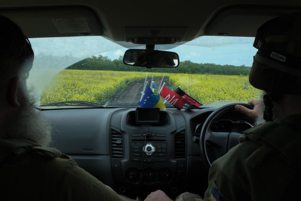 Ukrainian soldiers drive across colorful fields on the way to frontline positions on the southern front line on May 23, 2023. (Francis Farrell/The Kyiv Independent)