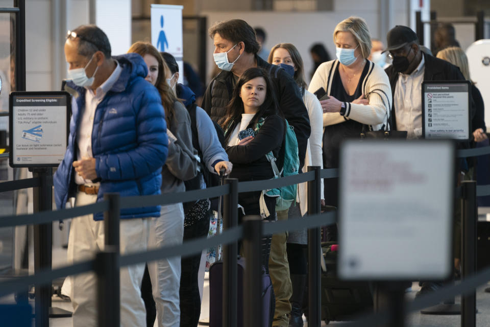 Passengers wait in line at the security checkpoint at Ronald Reagan Washington National Airport, Tuesday, April 19, 2022, in Arlington, Va. A federal judge's decision to strike down a national mask mandate was met with cheers on some airplanes but also concern about whether it's really time to end the order sparked by the COVID-19 pandemic. (AP Photo/Evan Vucci)