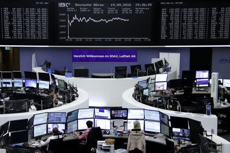 Traders work at their desks in front of the German share price index, DAX board, at the stock exchange in Frankfurt, Germany, September 19, 2016. REUTERS/Staff/Remote