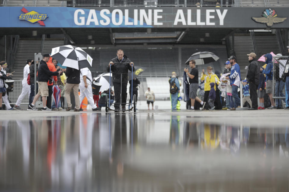 Fans and crew members walk through the rain soaked garage area as rain cancelled track activity for the Brickyard 400 auto race at Indianapolis Motor Speedway, in Indianapolis Saturday, Sept. 8, 2018. (AP Photo/Michael Conroy)