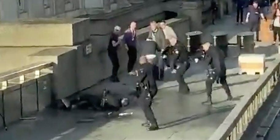 In this grab taken from video made available by @HLOBlog, a man is surrounded by police after an incident on London Bridge, in London, Friday, Nov. 29, 2019. A man wearing a fake explosive vest stabbed several people before being tackled by members of the public and then shot dead by armed officers on London Bridge, police and the city’s mayor say. Police say they are treating it as a terrorist attack. (@HLOBlog via AP)