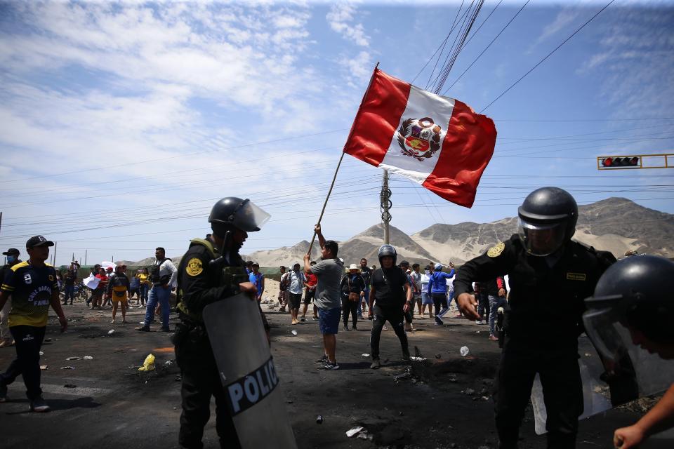 Simpatizantes del destituido presidente peruano Pedro Castillo protestan en la autopista Panamericana Norte mientras agentes de policía llegan para despejar la vía de escombros, en Chao, Perú, el jueves 15 de diciembre de 2022. El nuevo gobierno de Perú declaró 30 días de emergencia nacional el miércoles en medio de las violentas protestas que sobrevinieron a la destitución de Castillo y que suspenden derechos y libertades públicos en todo el territorio del país andino. (AP Foto/Hugo Curotto)