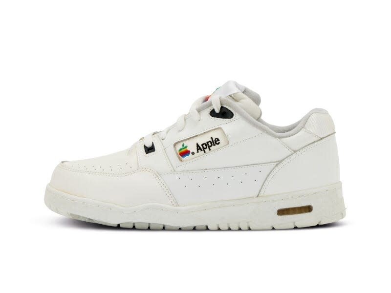 A pair of Apple sneakers. Mostly white leather with a vintage rainbow Apple logo on the sides.