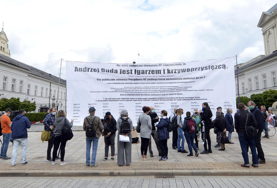 A small group of protesters with a banner reading "Andrzej Duda is a mocker and perjurer" hold a small rally against the narrow re-election of President Andrzej Duda to a second term, as shown by a near-complete count of presidential runoff votes, in Warsaw, Poland, Monday, July 13, 2020.(AP Photo/Czarek Sokolowski)