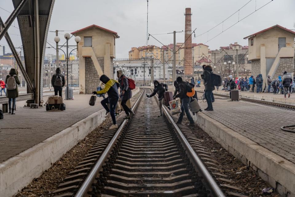 Un grupo de refugiados nigerianos atraviesan las plataformas en una estación, esperando poder abordar un tren (Bel Trew)