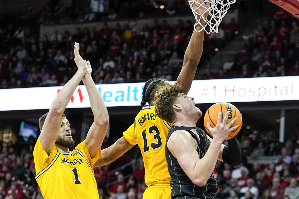 Wisconsin's Max Klesmit (11) shoots against Michigan's Hunter Dickinson (1) and Jett Howard (13) during the second half of an NCAA college basketball game Tuesday, Feb. 14, 2023, in Madison, Wis. (AP Photo/Andy Manis)