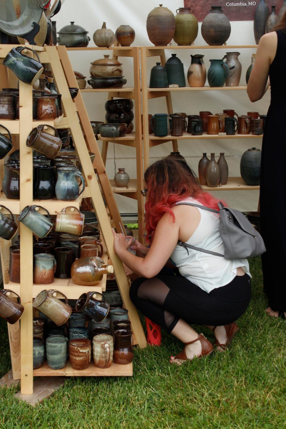 A patron looks at ceramic pieces during Art in the Park 2018