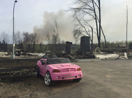 A pink car remains among the ruins of destroyed buildings after wildfires tore through the Waterways area of Fort McMurray, Alberta, May 5, 2016. Courtesy of Brad Readman/Alberta Fire Fighters Association/Handout via REUTERS