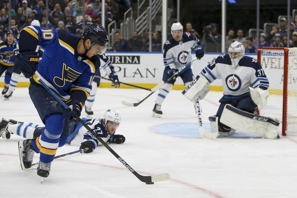 Winnipeg Jets goaltender Connor Hellebuyck (37) protects the goal while teammate Nikolaj Ehlers (27), of Denmark, reaches out for St. Louis Blues' Brayden Schenn (10) during the second period of an NHL hockey game Thursday Feb. 6, 2020, in St. Louis. (AP Photo/Scott Kane)